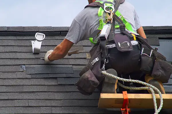 Roofer replacing damaged shingles